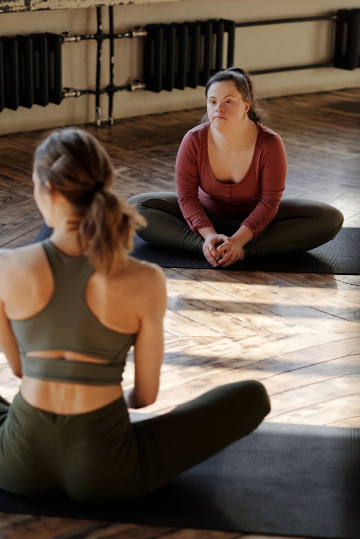 Two women practicing yoga indoors with focus on inclusivity and flexibility.